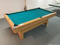 Pool table angled front-left view showing green felt and wood-grain frame