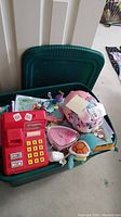 Overview of green storage bin containing assorted toys and books