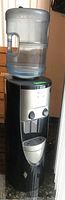 Full length view of the water cooler with a large water bottle on top, showing the general shape and size.
