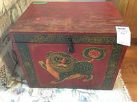 Front view of the antique wooden box showing the painted mythical creature and floral design.