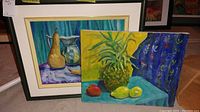Photo of two still life paintings by Martha Oldham, one framed (pears and jug) and one unframed (pineapple and fruits).