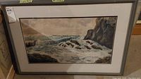 Full view of framed seascape painting showing ocean waves against rocky shore.
