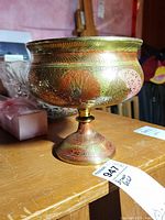 View of the brass vase showing detailed etched and painted design on the bowl and pedestal base.