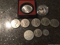 Overview of all seven coins, including the Olympic $5 coin in a red case, Platinum Jubilee coin in clear case, and five other coins.