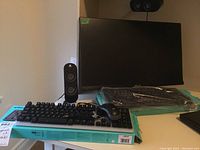 Computer monitor, keyboards, mouse, and speakers on a desk with some items still packaged.