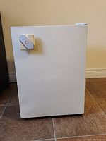 Front view of white mini fridge showing temperature control dial and minor surface wear.