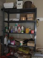 Metal shelving rack with various garden chemicals, spray bottles, boxes, and bags on four shelves.