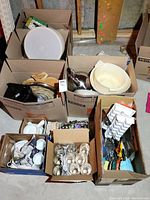 Boxes filled with assorted kitchenware items including bowls, kettle, and cutting boards.