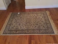 Full view of the 4x6 foot Oriental style rug with beige and brown floral patterns and fringe edges