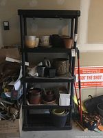 Full view of the shelving unit showing its four shelves and dimensions, with various plant pots and items stored (not included).