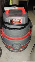 Shop Vac 5 gallon vacuum facing forward showing the handle, power cord, and part of the label on top.