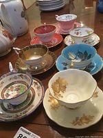 Six assorted bone china teacup and saucer sets arranged on table