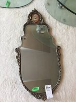 Front view of full mirror showing wood frame and oval painted detail at top.