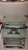 Top view of vintage Olympia typewriter inside the open case showing keyboard and carriage area.