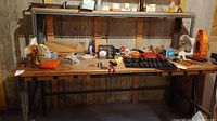 Front view of the large work bench showing wooden top surface cluttered with tools and small items.