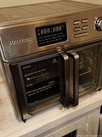 Front view of Kalorik barn door air fryer with dual glass doors closed and digital control panel.