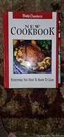 Book titled Betty Crocker's New Cookbook with red and white cover showing roasted meat and vegetables