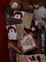 Photo of Christmas and fall decorations including penguin placemats, festive ornaments, and teddy bears inside a red box.