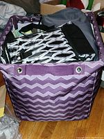 Purple chevron fabric storage cube filled with multiple insulated lunch bags with black and white pattern and gray cooler bag inside.