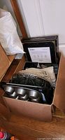 Open box showing two George Foreman grills, a muffin tin, a recipe box, chargers and a cut glass serving platter.