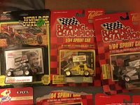 Photo showing 1/64 scale sprint cars in original Racing Champion packaging with red and black checkered branding.