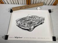 Full photo of the rolled and unrolled print featuring the Alfa Romeo cutaway illustration alongside the mailing tube and clips.