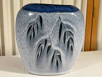 Oblong blue ceramic vase with embossed leaf design on textured surface, visible from a frontal angle.