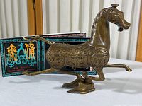 Side and front angled view of brass horse figurine with postcard set in background