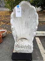 Full front view of heavy concrete shell garden decoration showing weathered surface and shape