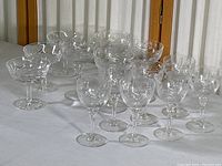 Full set of 14 crystal glassware pieces including sherbet, champagne, and cordial glasses arranged on white cloth.