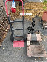 Photo showing red-handled black frame handtruck alongside carpet dolly and folding dolly.