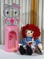 Hello Kitty water dispenser and Raggedy Ann doll together, showing item sizes and conditions.