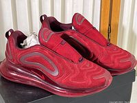 Pair of maroon Nike Air Max 720 slip-on shoes on a black Air720 shoe box, showing upper, side, and sole in good condition with light wear.