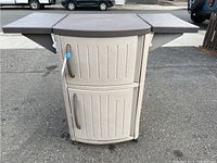 Front view of Suncast rolling outdoor bar with two storage doors and fold-out side panels extended.