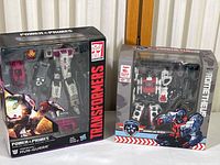 Boxed Power of the Primes Terrorcon Hun-Gurrr and Warning Line Prometheus figures side by side, showing packaging and figures through clear box windows.