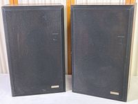 Pair of Fisher model 3110 vintage speakers with black fabric grille and wood veneer cabinets shown front side by side.