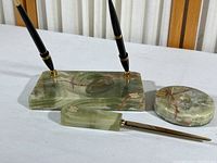 Vintage green onyx dual pen holder base with two black pens, letter opener with onyx handle, and round onyx paper clip holder on white surface.