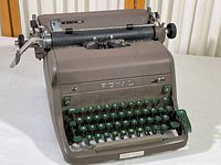 Front angle view of the brown metal Royal typewriter showing the green keys and manual controls including carriage return lever. Visible brand logo.