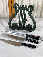 Two Wusthof chef's knives with sharpening steel and an iron music-themed cookbook holder.