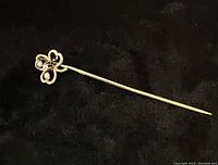 Full view of the stick pin showing the 3 leaf clover design on a dark background.