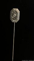 Front view of the white gold stick pin showing octagonal head with diamond and engraving detail on black background.