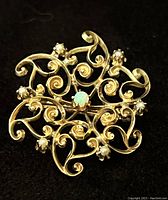 Front view showing circular open scrollwork brooch with central opal and accent stones