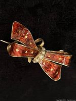 Front view of bow brooch showing red guilloché enamel and star pattern with central seed pearls