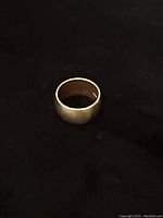 Top-down view of 14kt yellow gold band on black fabric.