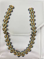 Full length view of the yellow gold tone choker necklace laid flat. Shows enamel floral accents alternating with gold tone links.