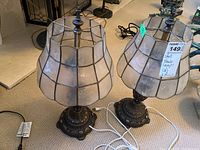 Pair of matching lamps with metal bases and capiz-style lampshades showing overall shape, size, and style.