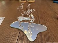Photo of clear crystal caribou figurine from slight side angle showing detail and reflection on mirror base