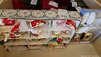 Compartments showing assorted small figural ornaments (mini Santas, candy cane, boot, gift shapes) in paper dividers