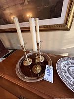 Three silver candlesticks with white taper candles on silver plate platter, with part of Spode plate visible