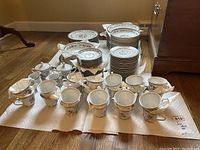 Overview of the incomplete Arlen china set with cups, plates, creamers, and bowls laid out on floor.